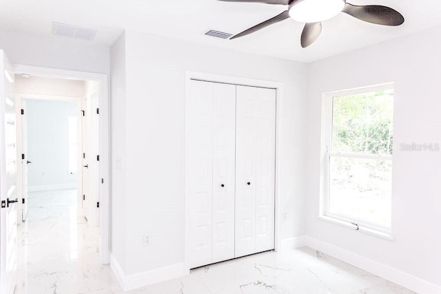 unfurnished bedroom with a closet, baseboards, marble finish floor, and visible vents