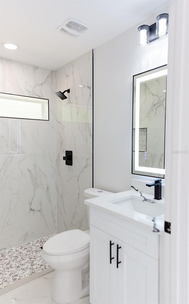bathroom featuring toilet, marble finish floor, visible vents, vanity, and a marble finish shower