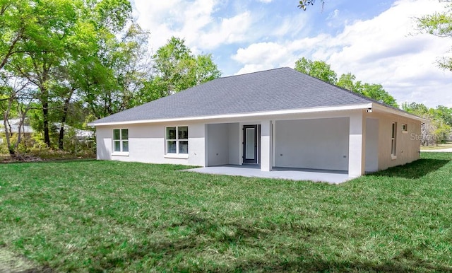 back of property with a yard, a shingled roof, a patio area, and stucco siding