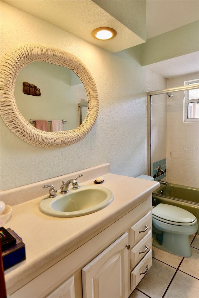 16850 SE 19th Ct, Summerfield, FL 34491 - bathroom with toilet, vanity, tile patterned flooring, a textured wall, and enclosed tub / shower combo