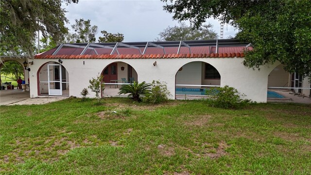16850 SE 19th Ct, Summerfield, FL 34491 - rear view of house featuring a lawn, glass enclosure, and stucco siding