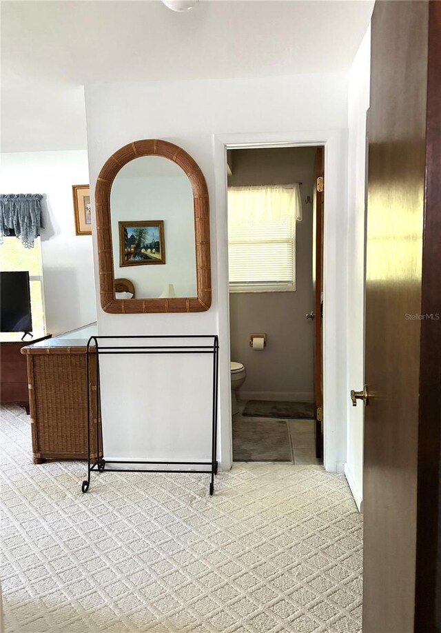 hallway featuring baseboards and light carpet