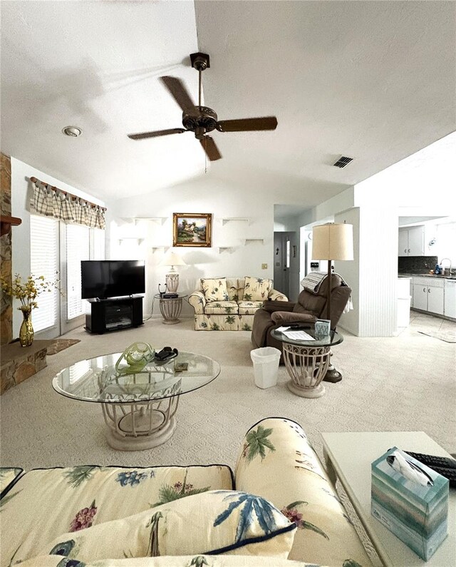 carpeted living area with ceiling fan, visible vents, a sink, and vaulted ceiling