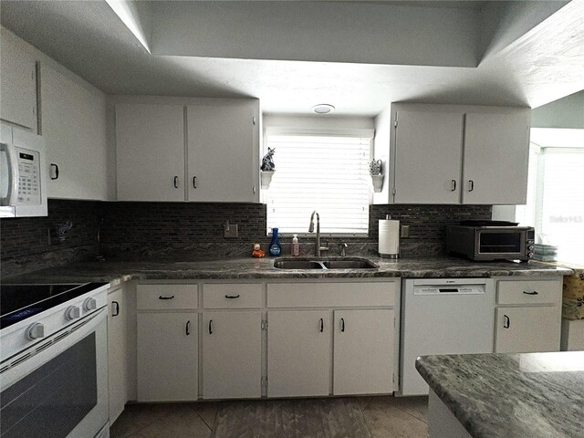 kitchen featuring a sink, backsplash, a healthy amount of sunlight, and white appliances