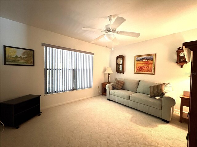 living area featuring baseboards, ceiling fan, and light carpet