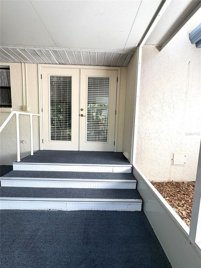 view of exterior entry featuring stucco siding and french doors