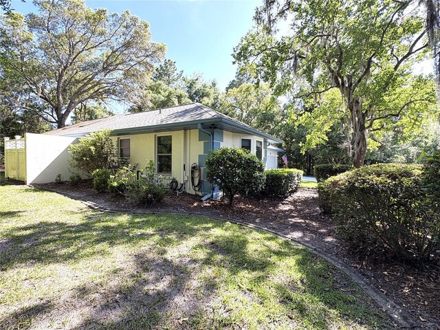 view of side of property with a lawn and stucco siding