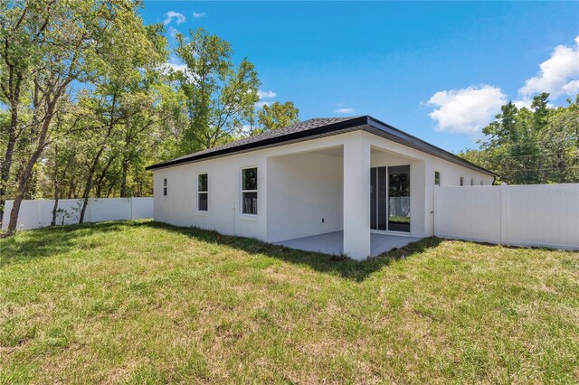 back of house featuring fence, stucco siding, a yard, and a patio area