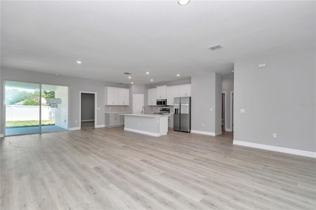 unfurnished living room featuring recessed lighting, baseboards, and light wood-style flooring