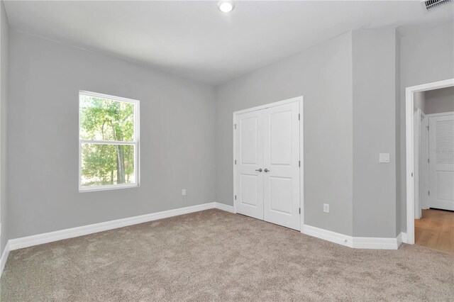 unfurnished bedroom with carpet flooring, baseboards, visible vents, and a closet