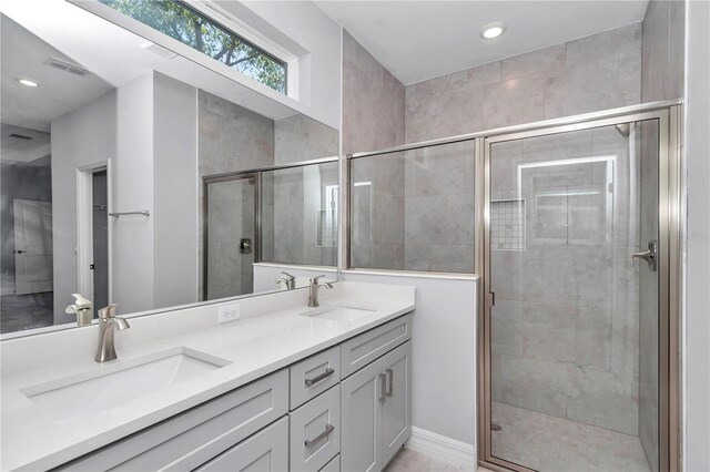 bathroom with a sink, a stall shower, double vanity, and visible vents