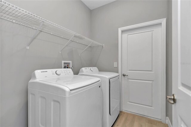 washroom with laundry area, light wood-type flooring, and washing machine and clothes dryer