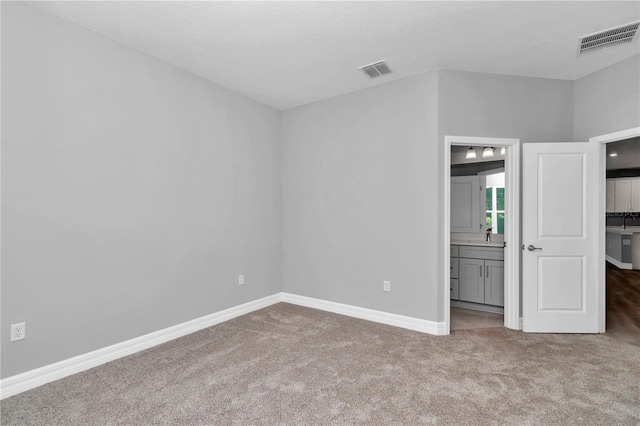 unfurnished bedroom with carpet flooring, baseboards, visible vents, and ensuite bathroom