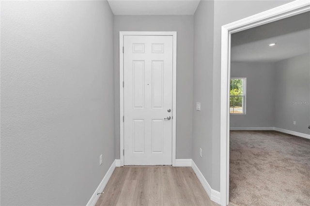 doorway to outside featuring baseboards and light wood finished floors