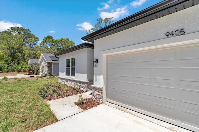 9405 SE 159th Ln, Summerfield, FL 34491 - view of exterior entry with stone siding, stucco siding, concrete driveway, an attached garage, and a lawn