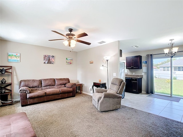 living area featuring light colored carpet, a chandelier, a ceiling fan, light tile patterned floors, and baseboards