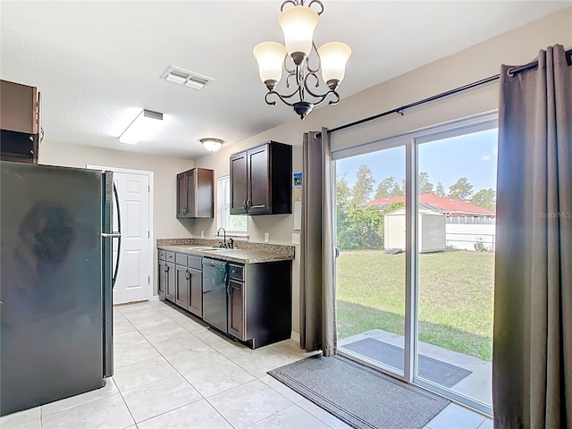 kitchen with freestanding refrigerator, dishwashing machine, a sink, light countertops, and a chandelier