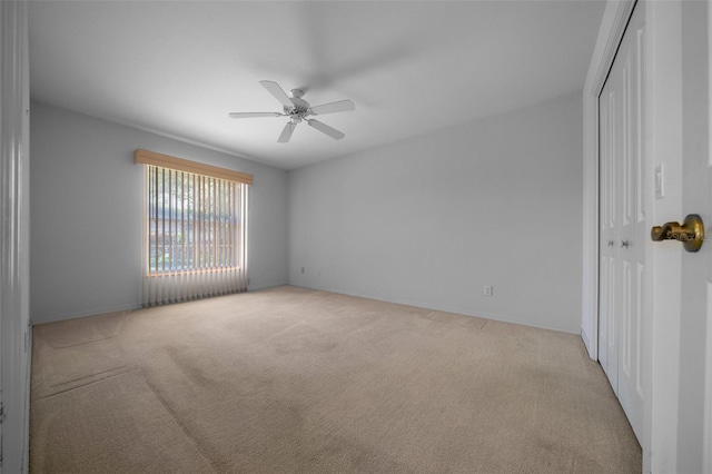 empty room featuring baseboards, ceiling fan, and light carpet