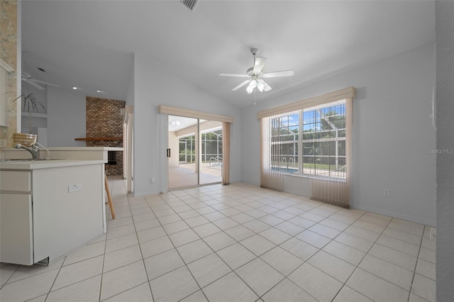 unfurnished living room with ceiling fan, a sink, baseboards, lofted ceiling, and light tile patterned flooring