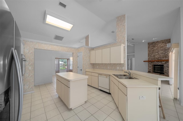 kitchen featuring a peninsula, light tile patterned flooring, a fireplace, white dishwasher, and stainless steel refrigerator with ice dispenser