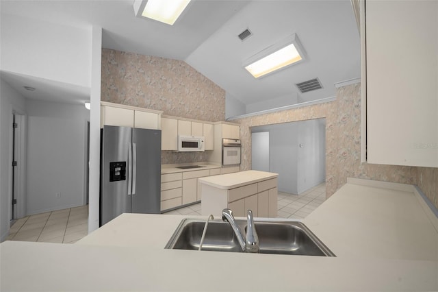 kitchen featuring visible vents, vaulted ceiling, a sink, wallpapered walls, and white appliances