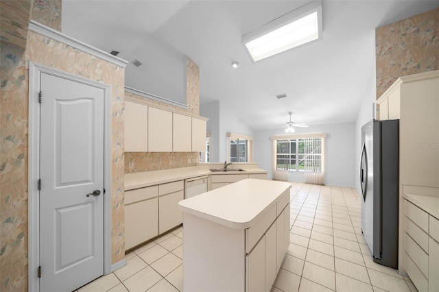 kitchen with a center island, vaulted ceiling, a sink, light tile patterned floors, and freestanding refrigerator