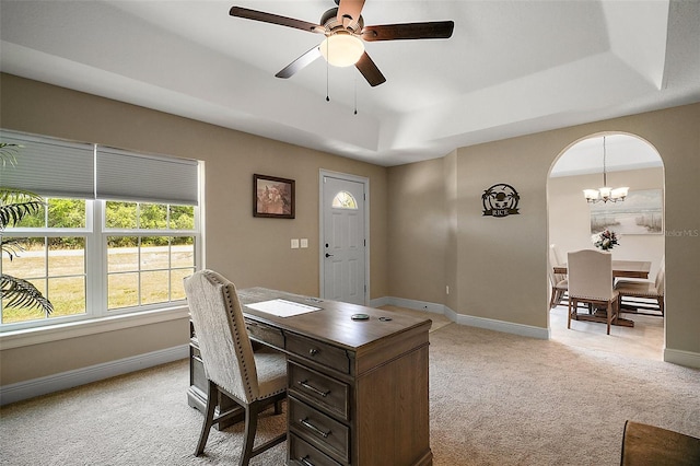 office featuring a tray ceiling, light colored carpet, and ceiling fan with notable chandelier
