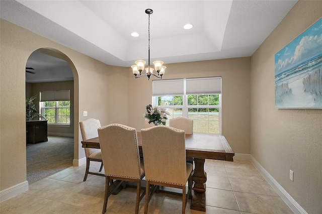 dining area featuring baseboards, arched walkways, a raised ceiling, and light tile patterned flooring