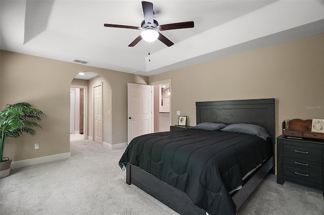 bedroom featuring light carpet, arched walkways, a ceiling fan, baseboards, and visible vents