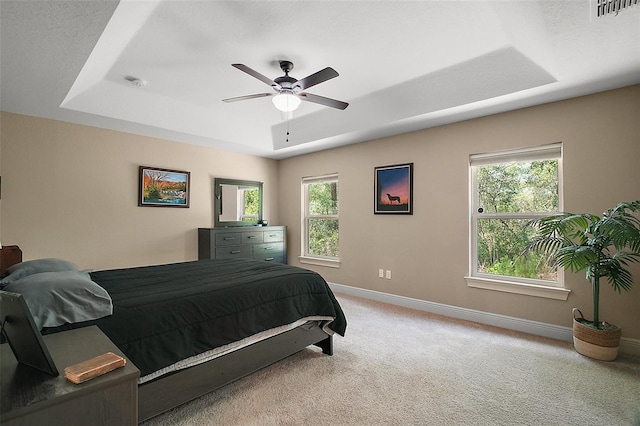 bedroom featuring multiple windows, visible vents, a raised ceiling, baseboards, and carpet floors