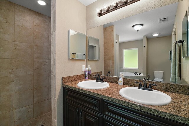full bathroom featuring visible vents, a sink, and a tile shower