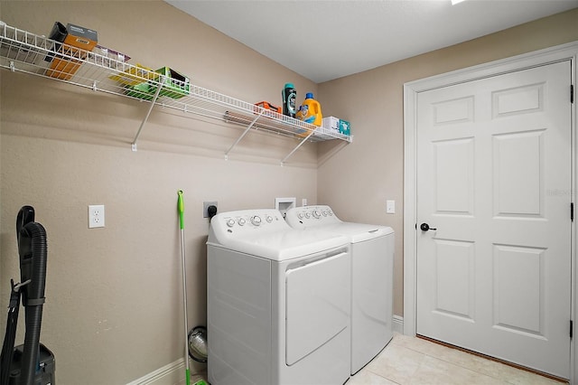 laundry room with baseboards, light tile patterned floors, laundry area, and washer and clothes dryer