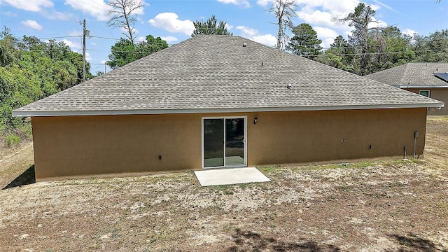 rear view of property with roof with shingles and stucco siding