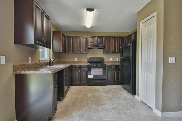 kitchen featuring under cabinet range hood, dark brown cabinets, a sink, and black appliances