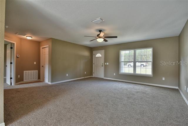 carpeted spare room with baseboards, ceiling fan, and visible vents