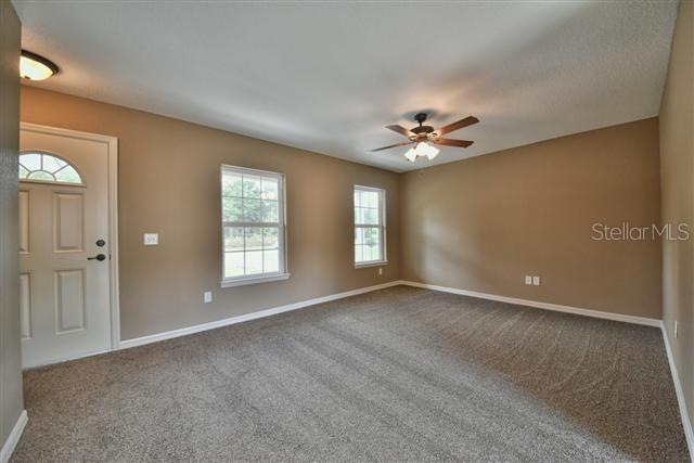 foyer entrance with a ceiling fan, baseboards, and dark colored carpet