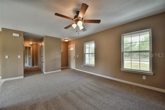 carpeted spare room with baseboards and a ceiling fan