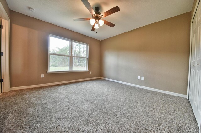 carpeted spare room with a ceiling fan and baseboards