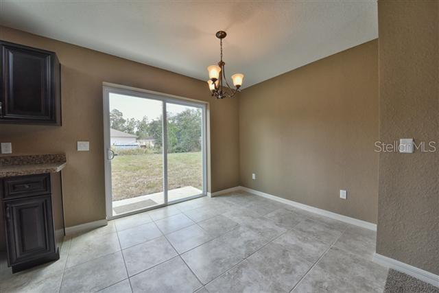 unfurnished dining area featuring light tile patterned floors, baseboards, and a chandelier
