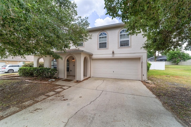 view of front of property featuring fence, a front lawn, concrete driveway, an attached garage, and stucco siding