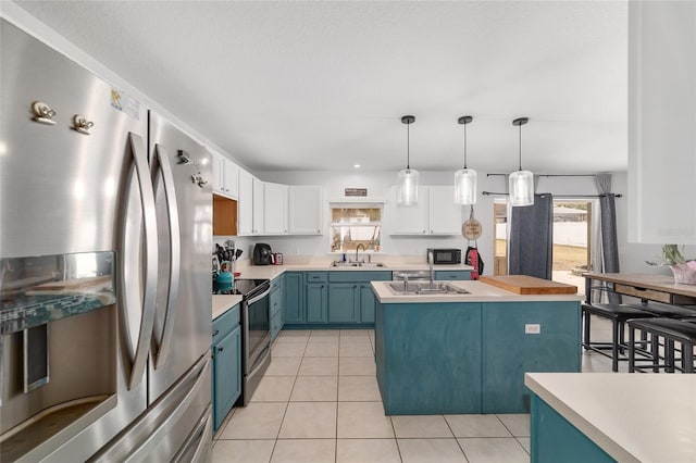 kitchen featuring light countertops, white cabinetry, blue cabinetry, and appliances with stainless steel finishes