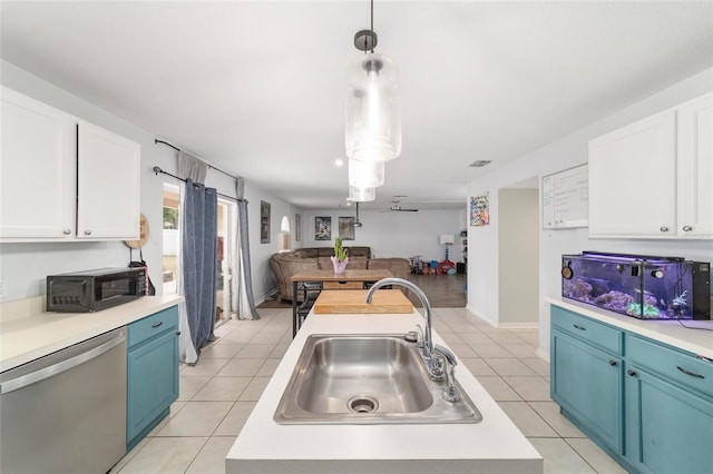 kitchen featuring stainless steel dishwasher, open floor plan, light countertops, a sink, and blue cabinetry