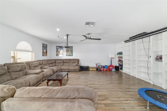 living room featuring visible vents, a ceiling fan, built in features, and wood finished floors
