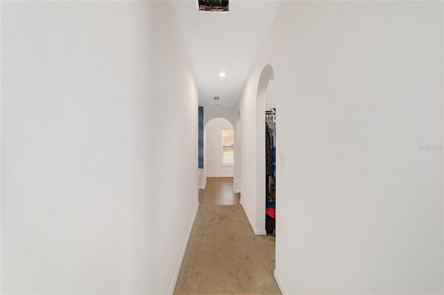 hallway featuring arched walkways, baseboards, light carpet, and recessed lighting