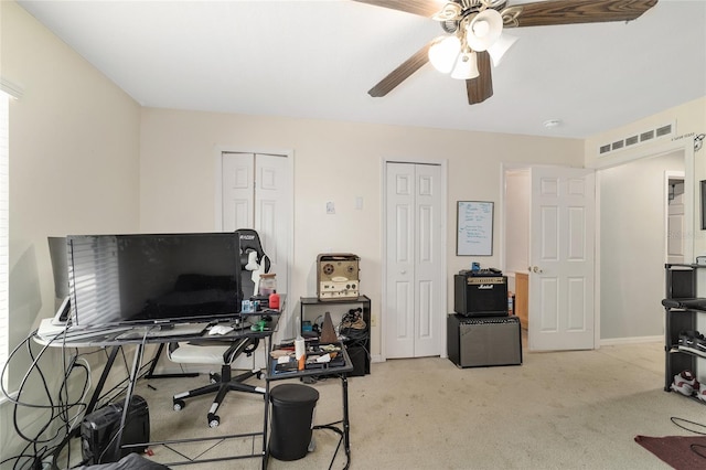 home office with light colored carpet, a ceiling fan, visible vents, and baseboards
