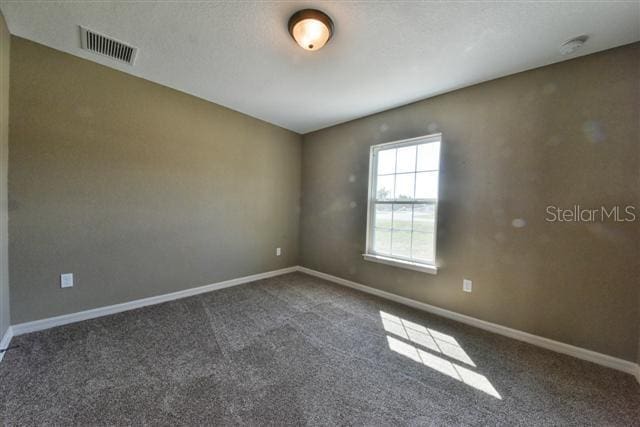 spare room with carpet flooring, baseboards, and visible vents