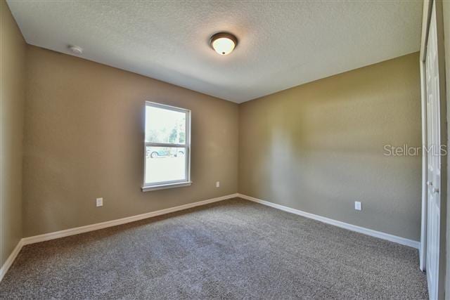 unfurnished room featuring carpet floors, a textured ceiling, and baseboards
