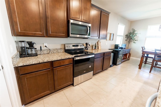 kitchen with light tile patterned floors, appliances with stainless steel finishes, baseboards, and light stone counters