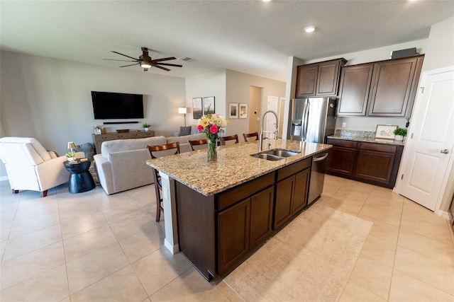 kitchen with a sink, a breakfast bar area, stainless steel appliances, a ceiling fan, and a center island with sink