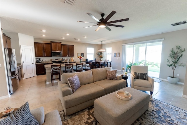living area featuring light tile patterned floors, baseboards, visible vents, and a healthy amount of sunlight